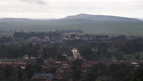 Eine-Totalaufnahme-Der-Ugandischen-Landschaft-Mit-Einer-Zuckerrohrverarbeitungsanlage-Und-Einer-Kleinen-Slumgemeinde,-Die-Darum-Herum-Errichtet-Wurde