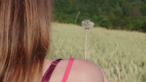 A-woman-blowing-a-dandelion-outside-in-the-green