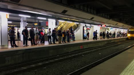 Rush-hour-commuters-wait-for-a-train-as-it-arrives-at-the-platform,-at-Central-Sdtation-in-Brisbane,-Australia