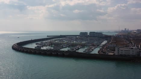 Aerial-dolly-shot-of-Brighton-Marina,-Pushing-over-the-Harbour-walls-as-a-dramatic-reveal---establishing-shot