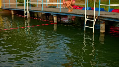 The-girl-is-jumping-to-the-lake-from-the-jetty