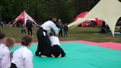 Men-wearing-traditional-clothes-and-showing-aikido-moves-to-their-students