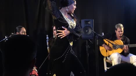 Bella-Chica-Bailando-Flamenco-Tradicional-Con-Un-Vestido-De-Terciopelo-Negro,-En-Un-Suelo-De-Madera