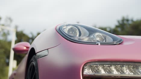 Front-headlight-of-pink-coated-Porsche-Boxster-two-seater-sports-car