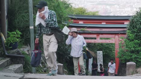 Japoneses-Subiendo-El-Tramo-De-Escaleras-En-El-Santuario-Fushimi-Inari,-Kyoto,-Japón---Tele-Cámara-Lenta