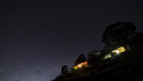 Zeitraffer-Von-Sich-Bewegenden-Sternen-Am-Nachthimmel-In-Der-Nähe-Einiger-Kleiner-Hütten,-Aufgenommen-In-4k