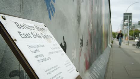 Close-Up-of-Berlin-Wall-at-East-Side-Gallery-with-Tourism-Sign
