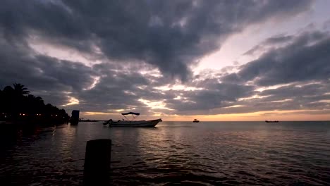 Ein-Zeitraffer-Bei-Sonnenuntergang-über-Dem-Meer-Mit-Einem-Boot,-Das-Sich-Auf-Einer-Kleinen-Insel,-Isla-Holbox-In-Mexiko,-Bewegt