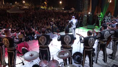 Wide-angle-shot-from-behind-Mariachi-band-on-stage-with-large-audience-in-Merida,-Mexico