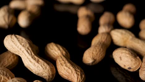 Bunch-of-peanuts-drop-from-above-onto-black-table