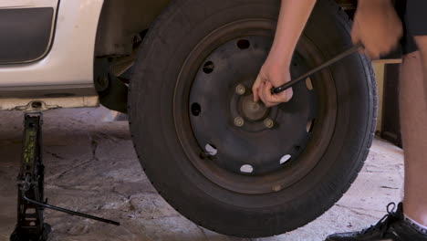 Man-unscrewing-nut-to-remove-flat-tire