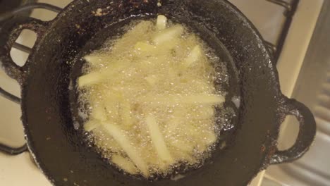 Homemade-French-fries-deep-frying-in-vegetable-oil-in-hot-wok,-overhead-view