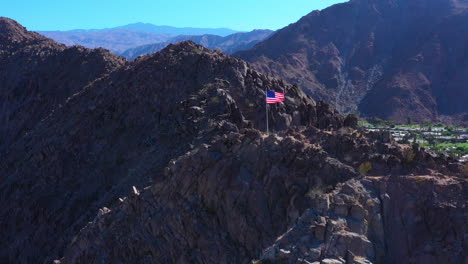 Aerial-Drone-Shot-of-American-Flag-with-Mountain-Range-Background