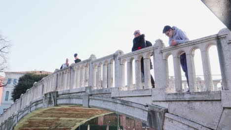 Tourists-enjoying-view-from-the-Ponte-Papadopoli-bridge,-over-the-Rio-Novo-Channel,-Venice,-Italy