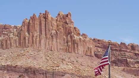 Slow-motion-shot-of-United-States-flag-blowing-in-the-wind-in-front-of-mountains-in-Capitol-Reef-National-Park-in-Utah,-USA