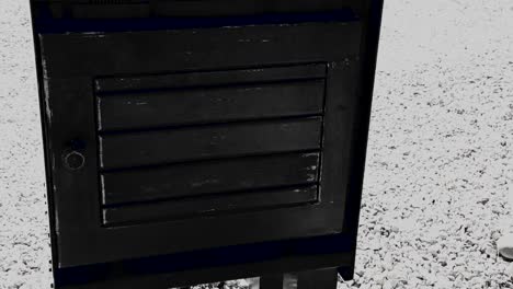 Black-and-White-of-an-old-fashion-newspaper-box-painted-black-without-a-newspaper