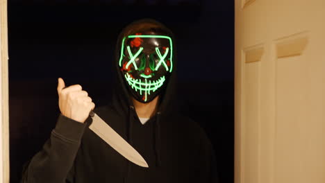 Ein-Gruseliger-Slasher-Killer-In-Einer-Generischen-Anonymen-Halloween-Horrormaske,-Der-Ein-Messer-Auf-Sein-Mordopfer-Zieht