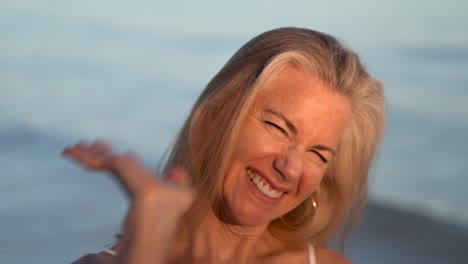 Closeup-of-mature-blonde-woman-pushing-her-hand-toward-the-camera-and-laughing