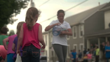 Girl-handing-out-free-candy-to-children-at-parade,-Slow-Motion