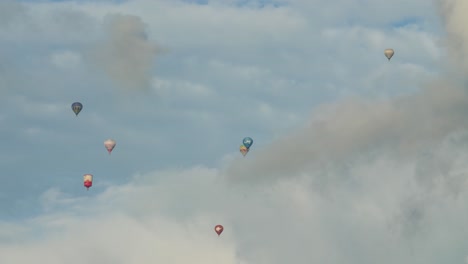Seven-small-hot-air-balloons-are-high-in-the-sky-between-the-clouds