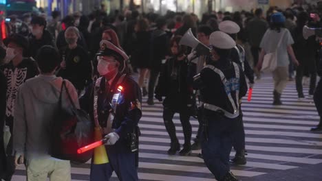 Group-Of-Policeman-Wearing-Masks-Holding-A-Megaphone-And-LED-Baton-Controlling-the-Crowd-At-Shibuya-Crossing-On-Halloween-Night-2020---Slow-Motion