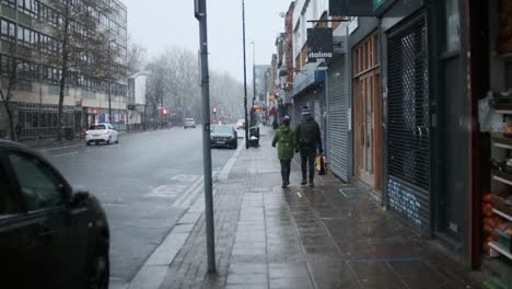 Adult-couple-dressed-for-winter-walking-down-snow-London-street-slow-motion