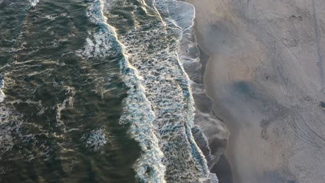 A-drone-shot-directly-over-a-quiet-beach-in-the-evening