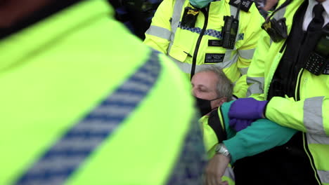 London-Metropolitan-police-officers-lift-up-and-carry-away-arrested-Extinction-Rebellion-climate-change-protestors-who-have-blocked-the-road-outside-parliament-in-Westminster