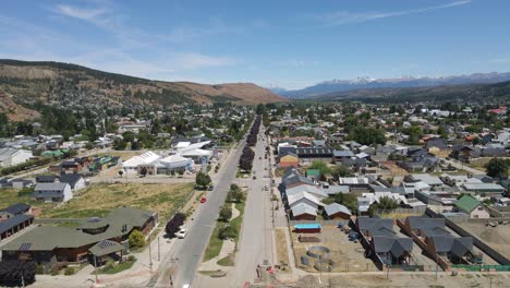 Dolly-in-flying-over-Esquel-city-main-street-with-Andean-mountains-in-background,-Patagonia-Argentina