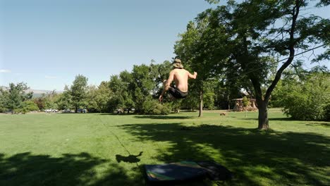 Young-caucasian-man-stands-and-walks-on-a-slackline,-in-the-park