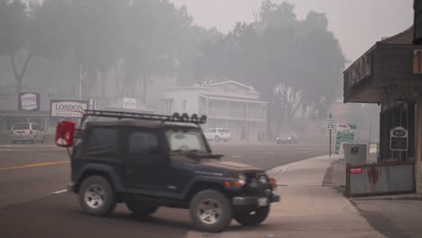 Vehicles-commute-through-smoky-street-in-rural-town,-creek-fire,-california