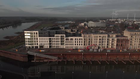 Aerial-sideways-pan-showing-exterior-facade-under-construction-of-luxury-residential-apartment-building-and-recreational-port-in-the-foreground-along-the-riverbed-of-the-IJssel-river