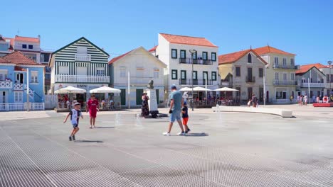 Children-play-between-fountains-in-front-of-colorful-houses-in-Aveiro,-Costa-Nova-in-Portugal