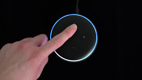Person-pressing-an-Amazon-Echo-Dot-smart-speaker-with-built-in-Alexa-voice-assistant