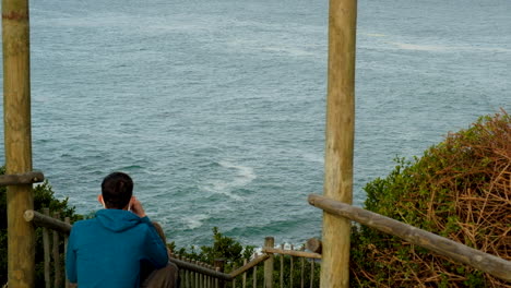 Couple-on-Hermanus-coastline-doing-whale-watching,-whale-sticks-head-out-of-water