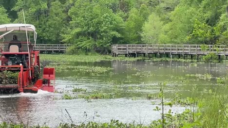 Bright-red-amphibious-mower-dredges-pond-at-Tom-Brown-Park-in-Tallahassee,-FL