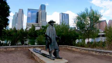 A-smooth-steady-clip-of-the-Stevie-Ray-Vaughan-Statue-on-the-banks-of-Lady-Bird-Lake-with-Austin-Skyline-behind