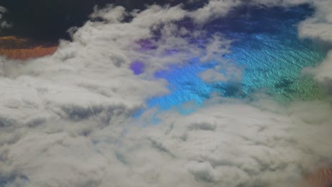 Rainbow-colors-on-planet-surface-from-above-with-white-clouds-in-the-atlantic-ocean-while-travelling-in-plane-for-holidays