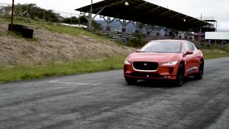 jaguar-i-pace-electric-orange-car-front-and-side-view-driven-on-racetrack