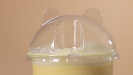 Close-up-on-the-Top-of-Fancy-Mango-Milkshake-Plastic-Cup,-Put-in-Black-Straw