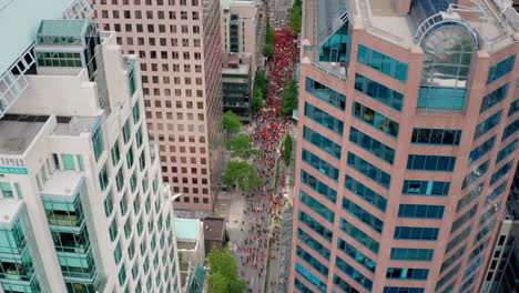 Huge-crowd-of-Indigenous-protesters-walking-below,-pull-back-tilt-aerial