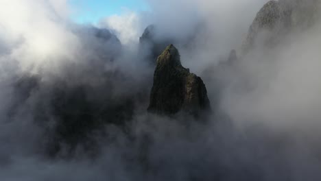 Drone-shot-tilting-upwards-over-the-cloudy-and-sunny-landscape-of-Pico-das-Torres-in-Madeira