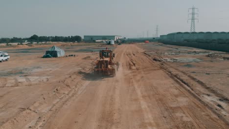 Tractor-Driving-Along-Dirt-Road-On-Construction-Site-In-Karachi,-Pakistan
