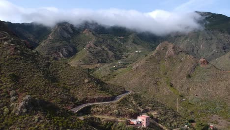 Massive-clouds-roll-over-hilltops-in-Tenerife-island,-aerial-view-of-majestic-valley