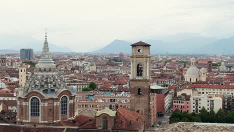 Church-tower-of-Turin-with-colorful-rooftops,-aerial-low-altitude-flying-view