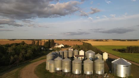 Aerial-forward-moving-drone-footage-high-above-a-small-family-operated-grain-farm-in-American-prairie-during-sunset