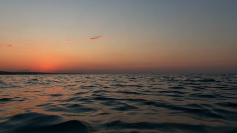 Beautiful-low-angle-sea-level-pov-from-sailing-boat-navigating-on-sea-water-surface-at-sunset