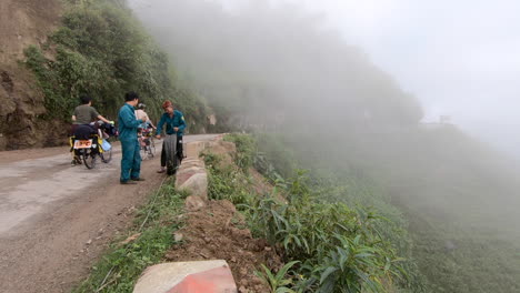 Two-vietnamese-travelers-walking-uphill-with-bicycles-in-a-foggy-day