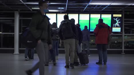 Pasajeros-Con-Equipaje-Mirando-La-Pantalla-Electrónica-En-El-Aeropuerto-De-Amsterdam-Schiphol-En-Países-Bajos,---Ancho