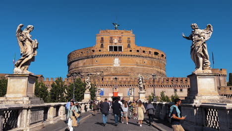 Ponte-Sant'Angelo-Bridge-with-many-crossing-people-during-sunny-day-in-Rome---Castel-Sant'Angelo-in-background